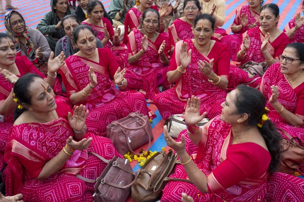 Hindu women devotees sing hymns as they gather at the confluence of the Ganges, the Yamuna and the mythical Saraswati rivers, a day before the official beginning of the 45-day-long Maha Kumbh festival, in Prayagraj, India, Sunday, Jan. 12, 2025. (AP Photo/Ashwini Bhatia)